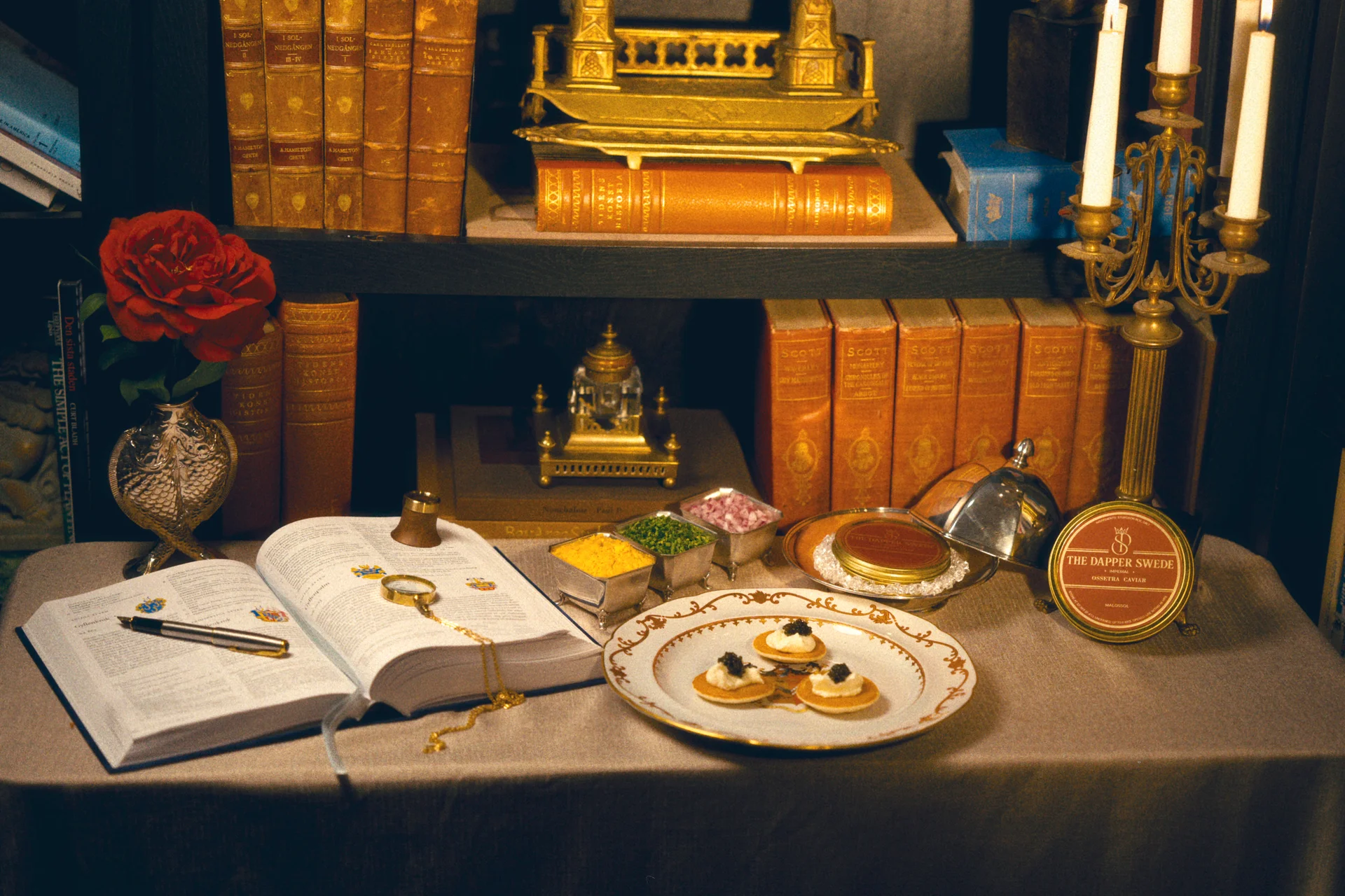 Ossetra caviar served beside a library of books, candles and a red rose