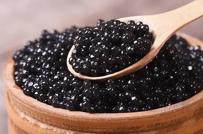 Black caviar in a wooden bowl with a serving spoon