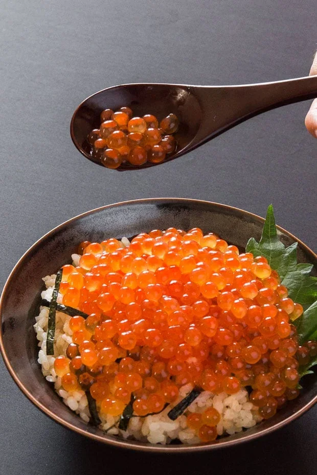 Orange salmon roe served over rice with a wooden spoon