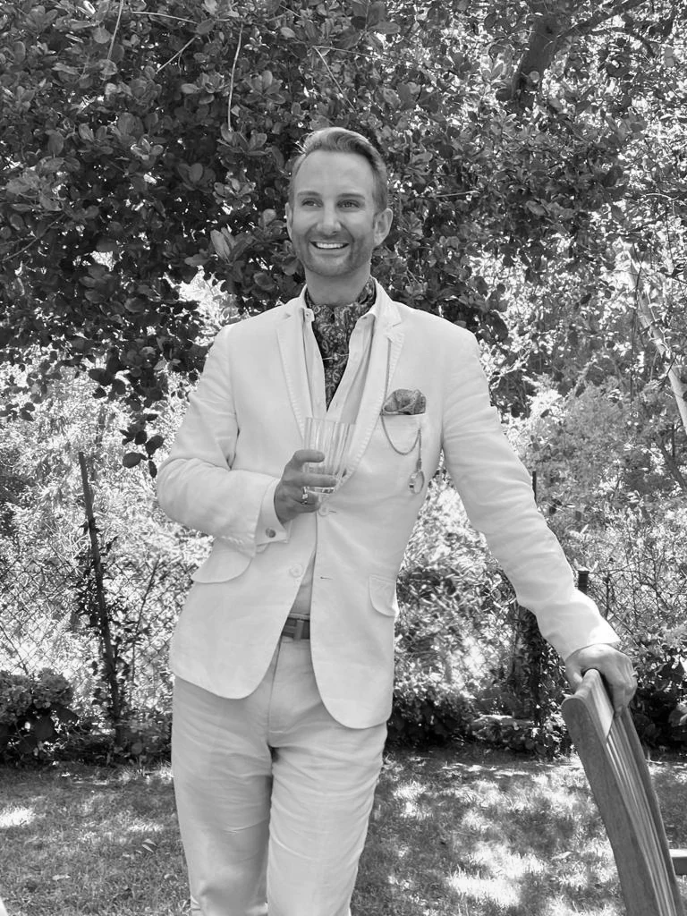Black-and-white portrait of Johan in a white suit in the garden